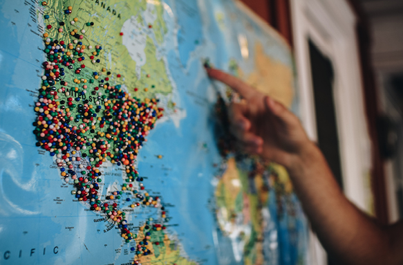 A close-up photograph of someone pointing on a map of the world.